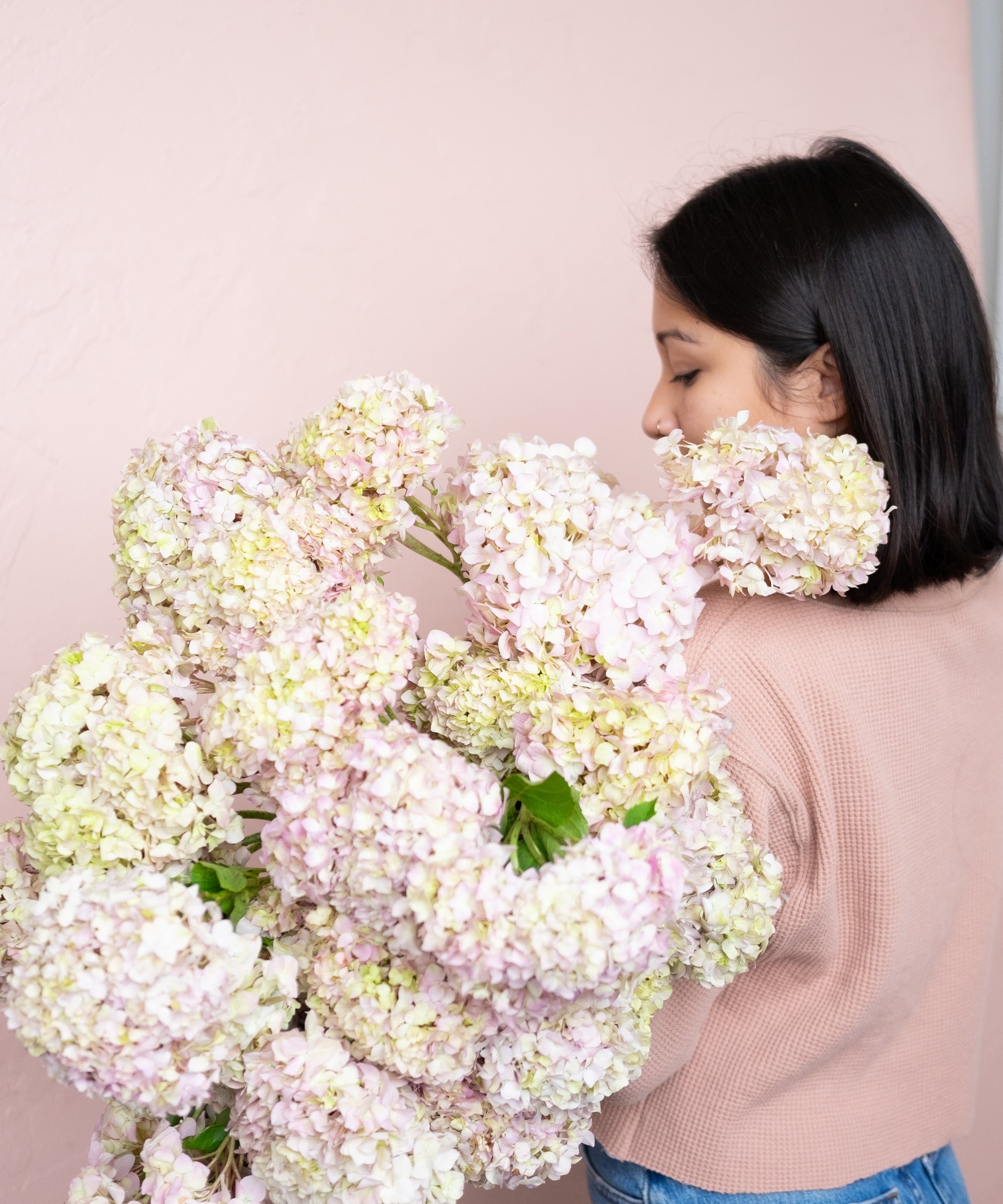 Woman holding a large bouquet of white flowers against a plain background