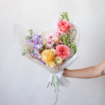 Bouquet of colorful flowers held against a plain background