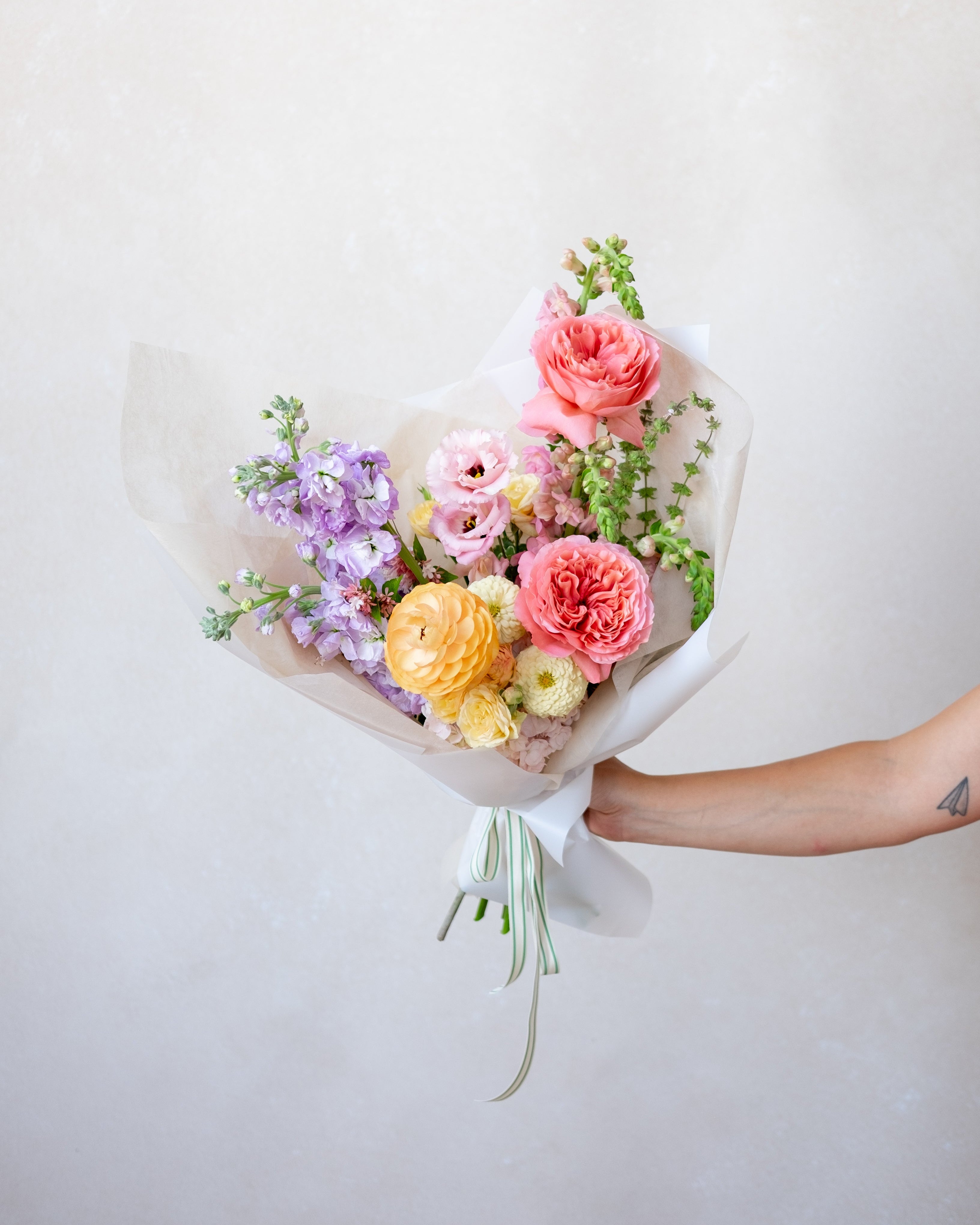 Bouquet of colorful flowers held against a plain background