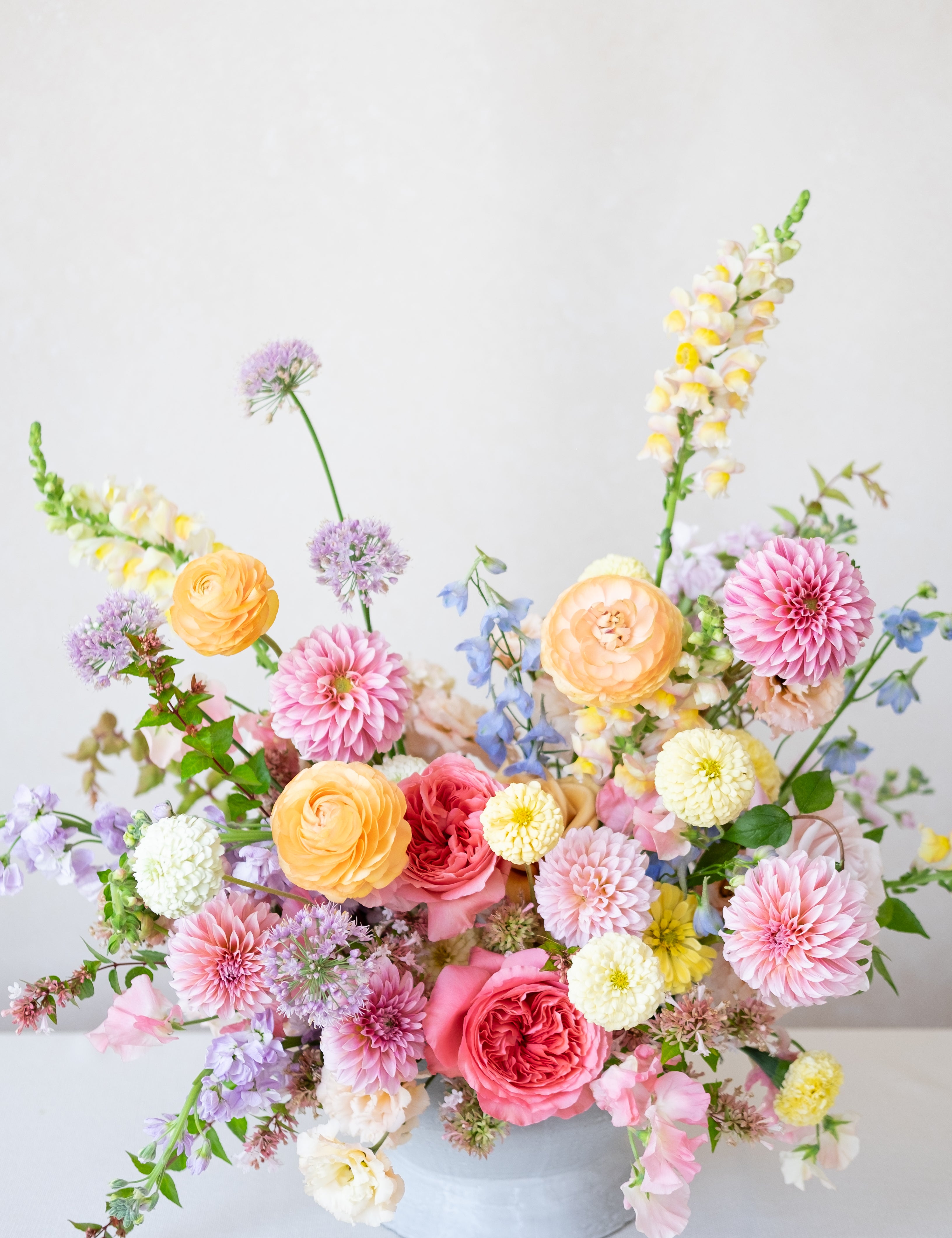 Colorful flower arrangement in a white vase on a light gray background