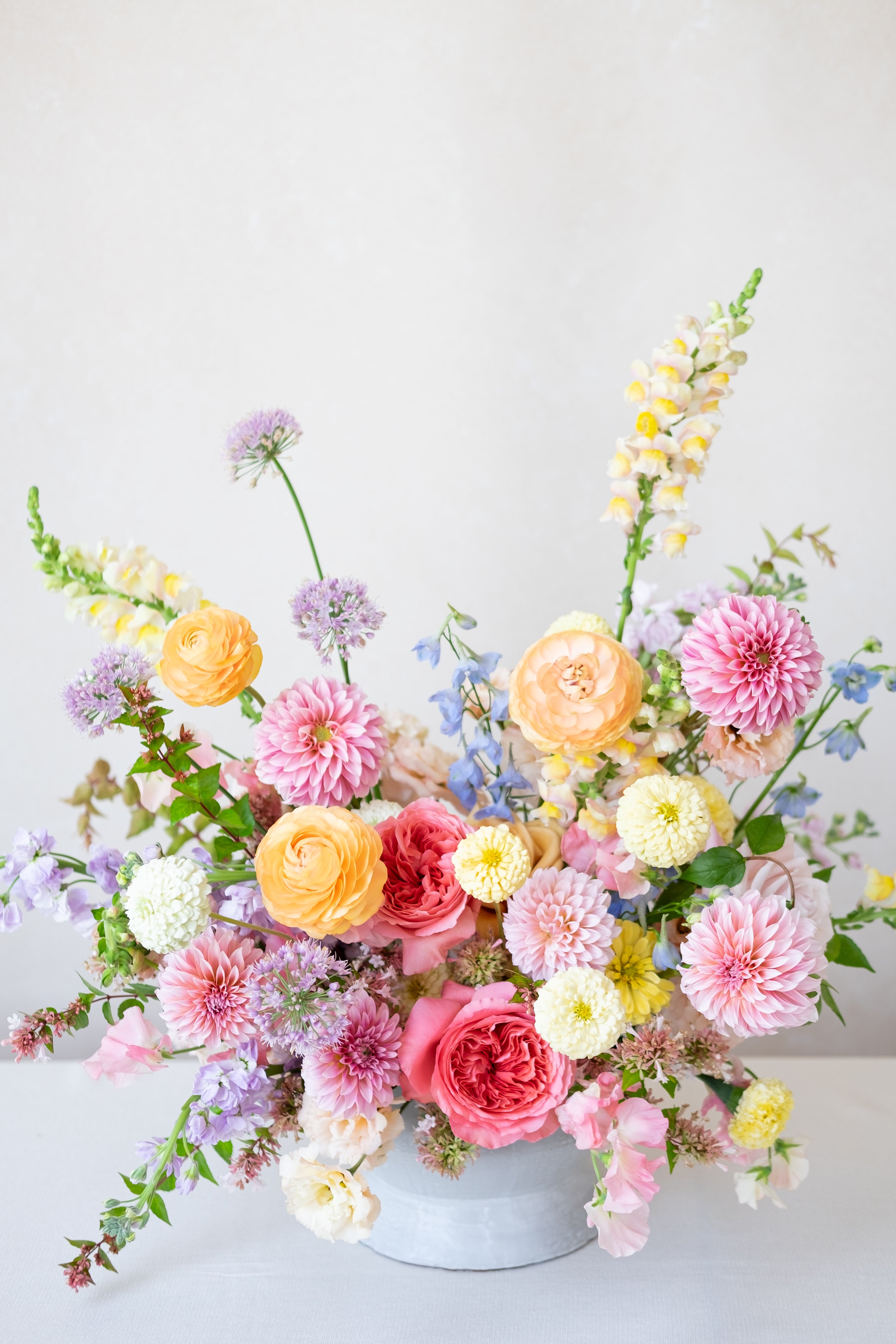 Colorful flower arrangement in a white vase on a light gray background