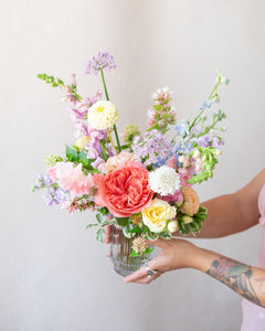 Person holding a colorful bouquet of flowers against a plain background