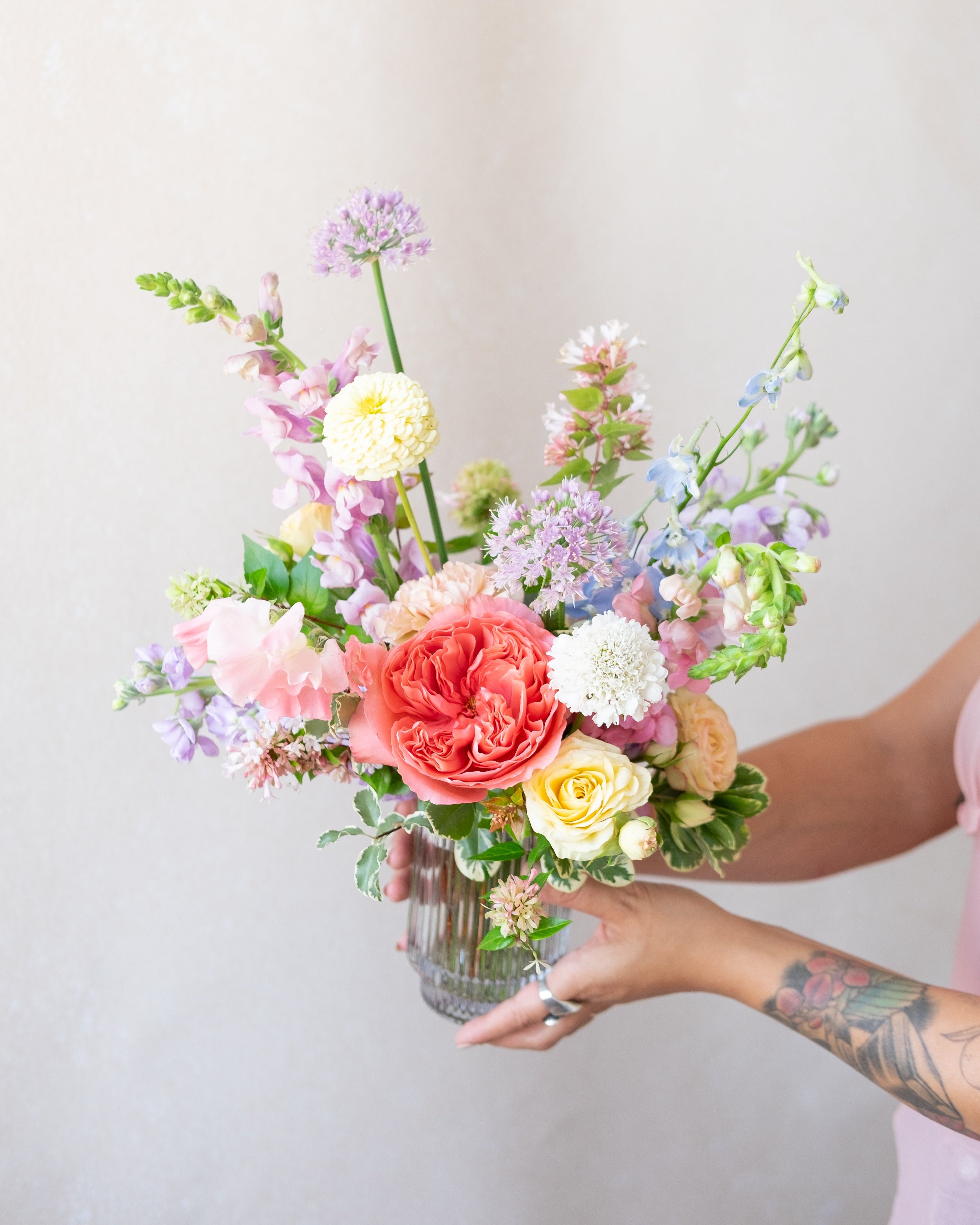 Person holding a colorful bouquet of flowers against a plain background