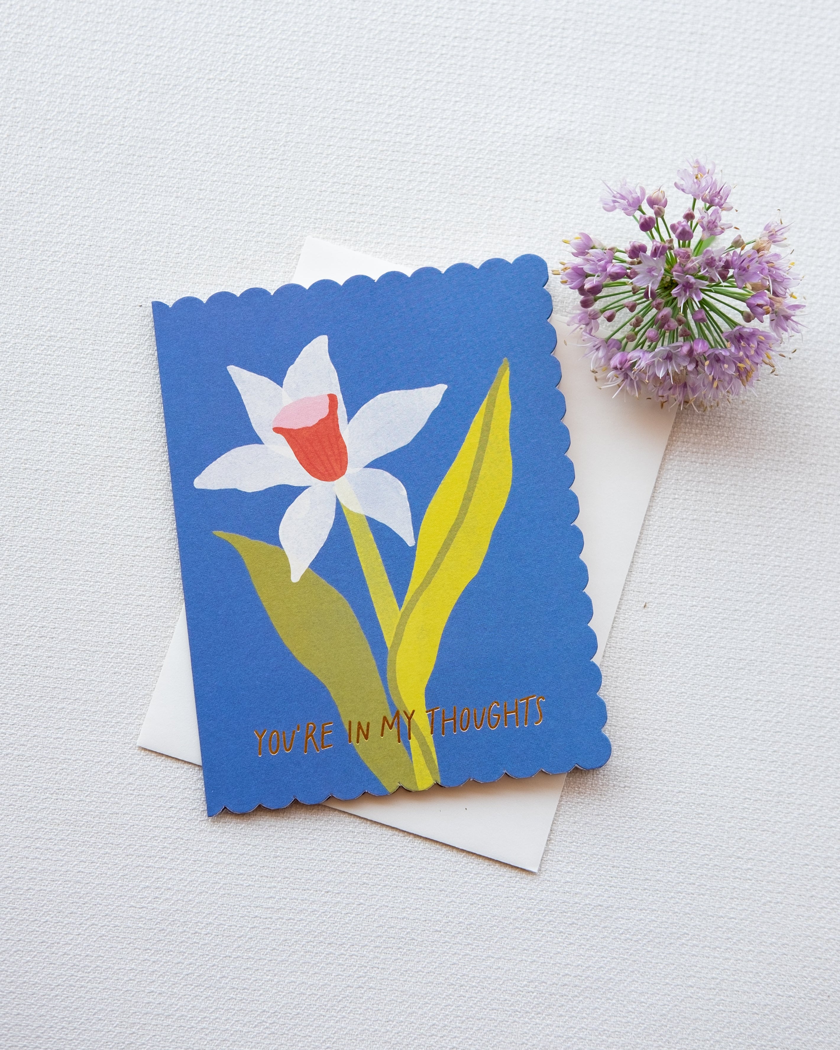 Greeting card with a blue border and white flower illustration on a light gray background